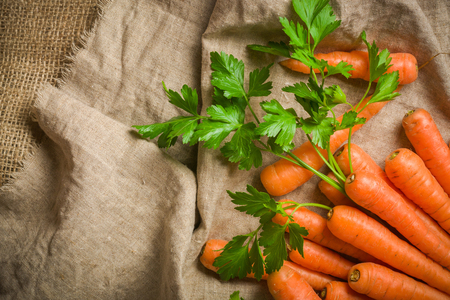Carrots of various sizes stacked in a pile on a burlap background. Washed and ready to eat. View from aboveの写真素材