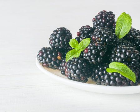A bunch of dewberries on a white plate. Light background.の写真素材