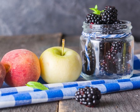 Blackberry and fruit on an old wooden table. Blue textiles. Copy space.の写真素材