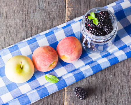 Blackberry and fruit on an old wooden table. Blue textiles. Copy space.の写真素材