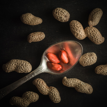 Fresh peanuts in peel and shell. Dark wooden background. Vegetarian food.の写真素材