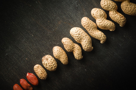 Fresh peanuts in peel and shell. Dark wooden background. Vegetarian food.の写真素材
