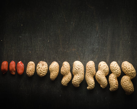 Fresh peanuts in peel and shell. Dark wooden background. Vegetarian food.