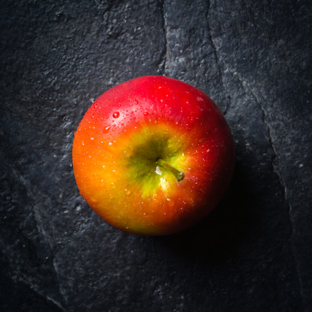 Ripe autumn apples red and yellow on a black stone background from slate. Harvesting. Vitamins are good for health. Copy space.の写真素材