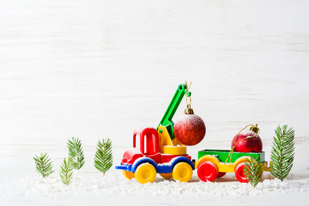 A small toy car is a crane. New Year and Christmas background. Mini Christmas trees from real spruce. Santa Claus made of paper. A blank for a postcard or a posterの写真素材