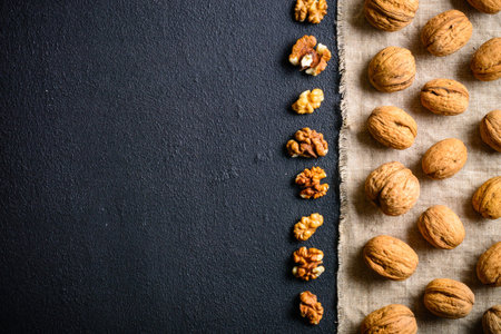 Walnuts on a black slate. Whole and peeled nuts. Walnuts spread out evenly. Copy space.
