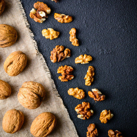 Walnuts on a black slate. Whole and peeled nuts. Walnuts spread out evenly. Copy space.