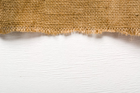 Burlap lying on a white wooden table. Preparation for the designer. Plenty of room for text and photoの写真素材