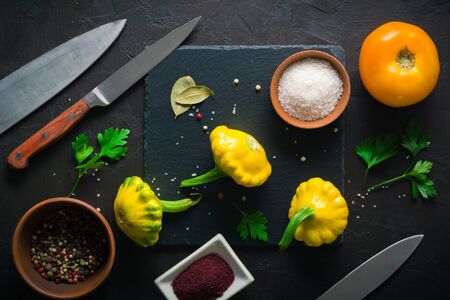 Yellow and green squash lying on a dark kitchen table. Seasonings and spices for cookingの写真素材
