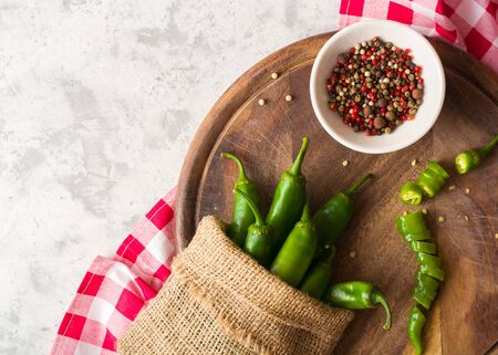 A few green hot peppers in a pouch shot from above on a light stone background and cutting board. Plenty of space for textの写真素材
