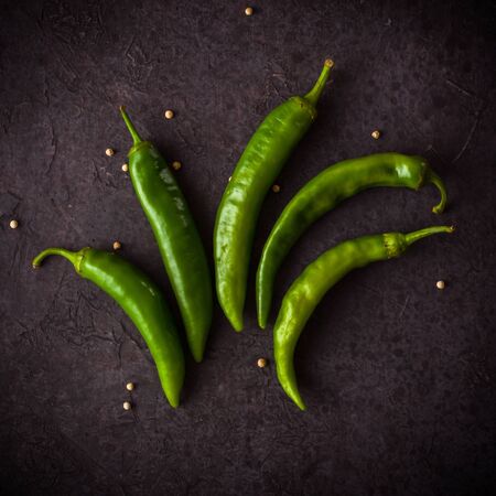 A few green hot peppers shot from above on a dark stone background. Plenty of space for textの写真素材