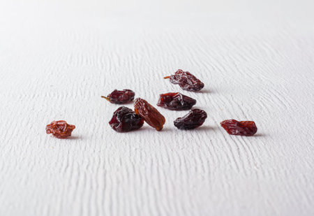 A variety of peeled walnuts and raisins on a white wooden background. View from above. Plenty of...