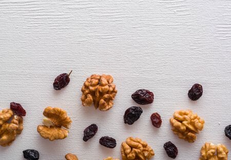 A variety of peeled walnuts and raisins on a white wooden background. View from above. Plenty of space for text.の写真素材