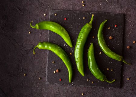 A few green hot peppers shot from above on a dark stone background. Plenty of space for text.の写真素材