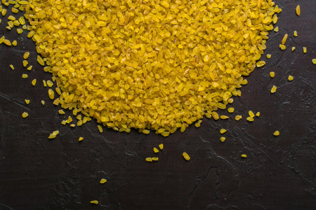 Bulgur lying in a heap on a dark background. Useful organic food for breakfast or diet. Plenty of...