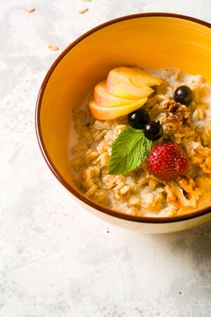 Morning oatmeal for breakfast. Early morning and healthy diet food. Proper nutrition. White stone background. Plenty of space for textの写真素材