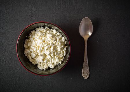 Fresh white cottage cheese in a bowl on the table. Tasty and healthy breakfast. dark stone surface. View from above. A lot of space for textの写真素材