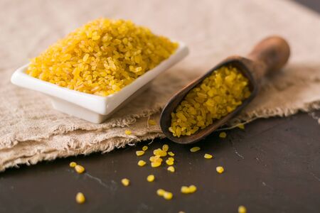 Bulgur on a dark background. wholesome organic food for breakfast or diet. Natural fabrics and earthenware. Copy space.の写真素材