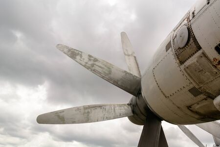 Part of the fuselage of the old military plane with the propeller closeup against the background of an empty and gray skyの写真素材
