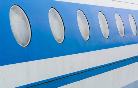 A number of perspective portholes of a passenger plane in blue and white.の写真素材