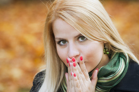Young blond girl feeling cold outdoors over yellow leaves in autumn. 25-30 years oldの写真素材