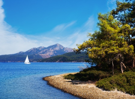 Seascape of Aegean Sea with a shore and a yacht over the mounains on it, Turkeyの写真素材