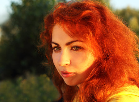 Beautiful red haired girl in yellow vest outdoors
