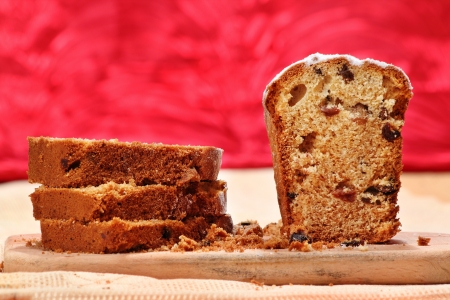 Cut cake with raisins on a breadboard over red backgroundの写真素材