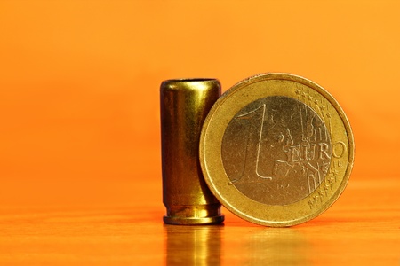 A bullet with a euro coin leaning on it symbolizing a paid war conceptの写真素材