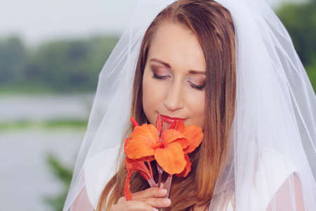 Young bride smelling the red flowerの写真素材