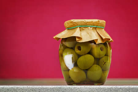Closeup of a glass of preserved olives over red backgroundの写真素材