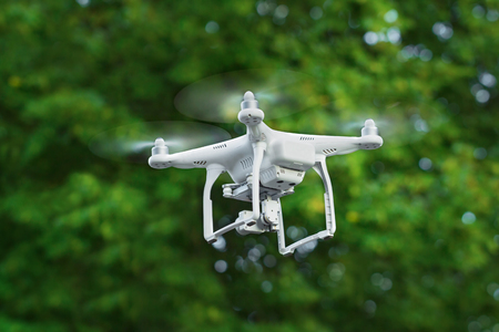 KIEV, UKRAINE - JULY 14, 2016: Closeup of a white drone quadrocopter flying over the trees in the park.のeditorial素材