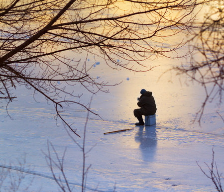 Unidentified fisherman fishing on the ice of a frozen river.の写真素材
