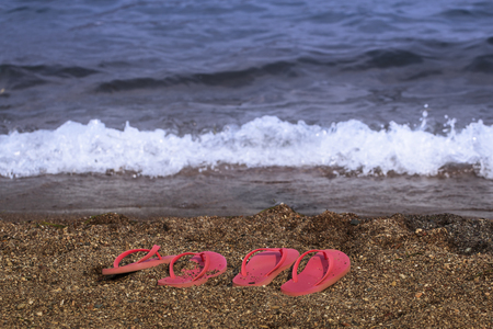 Two pairs of pink flip flop slippers left at the beach by a couple who went swimming in the Aegean sea in Turkey.の写真素材