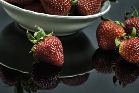 Fresh Strawberries in White Bowl on Black Plexiglassの写真素材