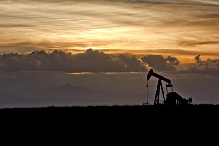 Dramatic Sunset Skies Over Oil Field and Oil Wellの写真素材