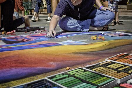Sidewalk Chalk Artist Drawing with Rainbow of Chalkのeditorial素材