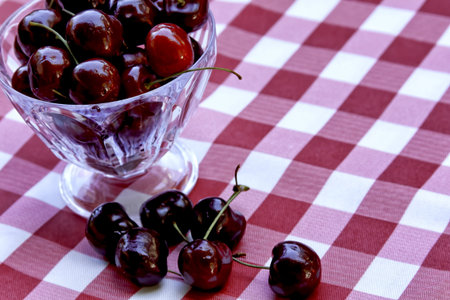 Red Cherries in Glass Cup on Checkered Tablecloth, From Above