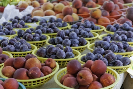 Peaches, plums and nectarines in baskets for sale at local marketの写真素材