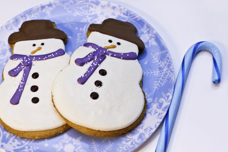 Snowman cookies on blue plate with blue candy cane