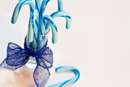 Blue candy canes standing in glass with blue glitter ribbon