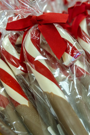 Chocolate dipped candy canes in package with red bowの写真素材