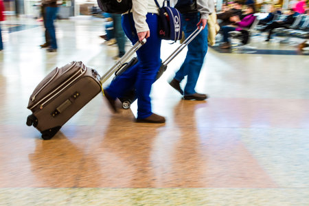 People walking quickly in airport pulling luggageのeditorial素材
