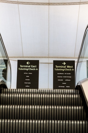 Woman walking quickly pulling green and black luggage in busy airportのeditorial素材