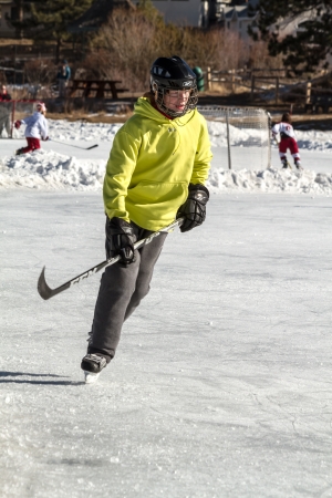 Teenage boy playing hockey on outdoor skating rinkのeditorial素材
