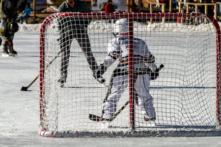 Young boy defending hockey goal, playing hockey on outdoor skating rinkのeditorial素材