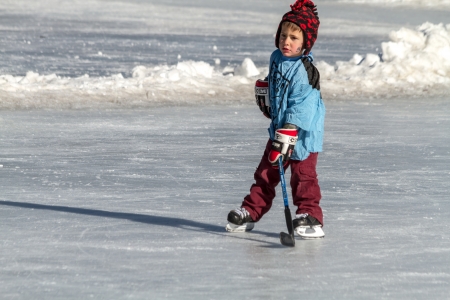 Young boy dressed in hockey gear, playing hockey on outdoor rinkのeditorial素材