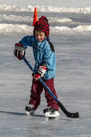Little boy learning to skake and play hockey on outdoor skating rinkのeditorial素材