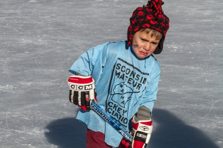 Little boy crying after falling playing ice hockey on outdoor skating rinkのeditorial素材