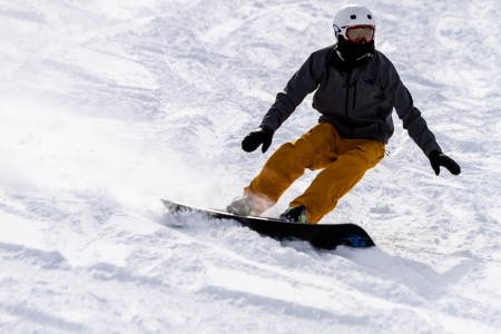 Male snowboarder in brightly colored ski pants skiing down hill at Ski Days during 50 Year Steamboat Springs winter celebrationのeditorial素材